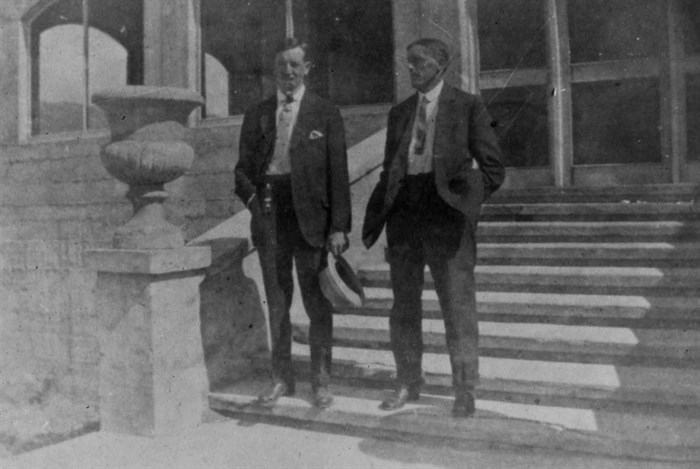 Two men standing on the front steps of the hotel.