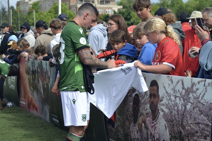 A Cavalry player signing an autograph for a fan after the match. 
