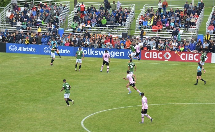 Players go for a header while the crowd is on the edge of their seats. 