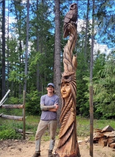 Armstrong artist and carver Kamron Garbe stands beside his sculpture in Mabel Lake. 