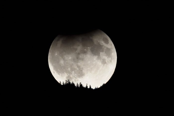 The full harvest moon over Summerland is seen in a partial lunar eclipse. 