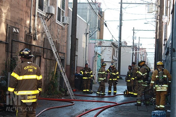 Firefighters prepare to overhaul the upper floors of the building housing Fibonacci Roastery and Cafe and Hooked on Books at 225 and 219 Main Street in Penticton after fire broke out this morning, September 30.