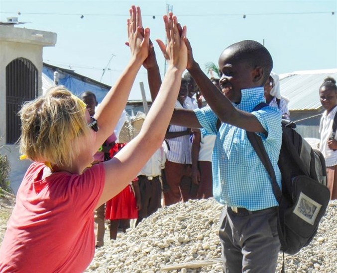 UBC Okanagan Human Kinetics student Paige Marzinzik high fives a young boy during her last visit to Haiti.