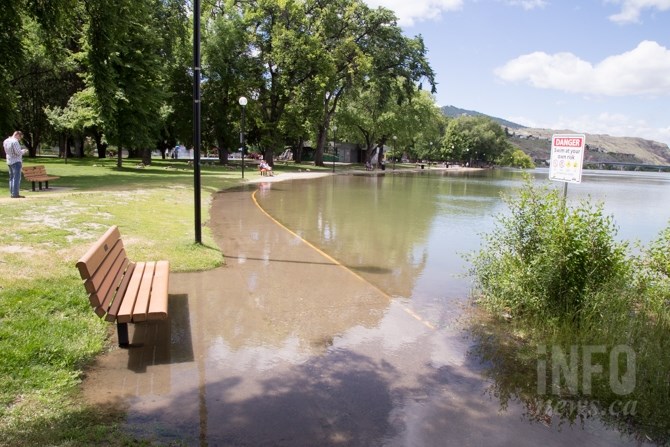 Water surrounds a bench and walkway at Riverside Park. 