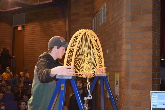 James Dessert testing his spaghetti bridge.