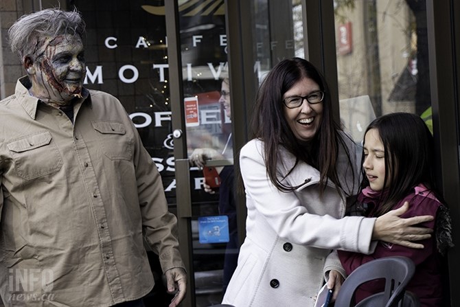 Jessica Gunnlaugson shields 10-year-old Jasmira Hasler from zombie Kelly Glanzer. This is Glanzer's first time participating in the walk, but has been a long-time zombie fan.