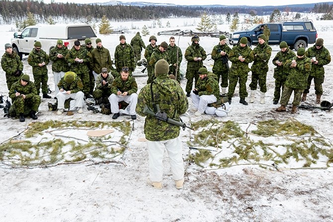 Lt. Max Birkner (centre) uses a map made from sticks and cardboard to illustrate their plan of attack.