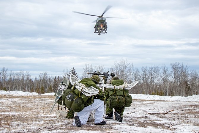 Four soldiers line up as practiced waiting for the helicopter to take them from their base camp to the drop off point where they will start the combat training.