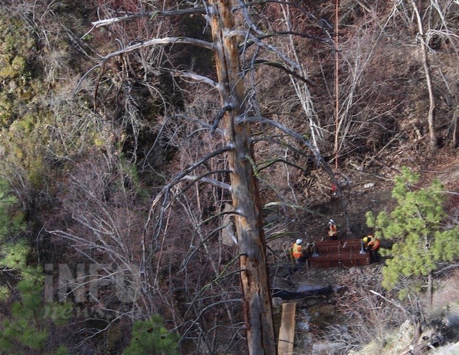 A crew works to release a wooden bridge airlifted into Hardy Falls Regional Park, Thursday, April 11, 2019.