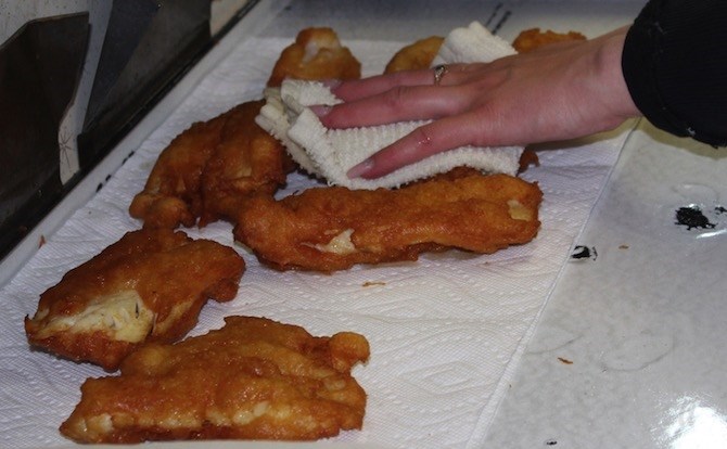 Sam Bell pats the cooking oil off the cod.