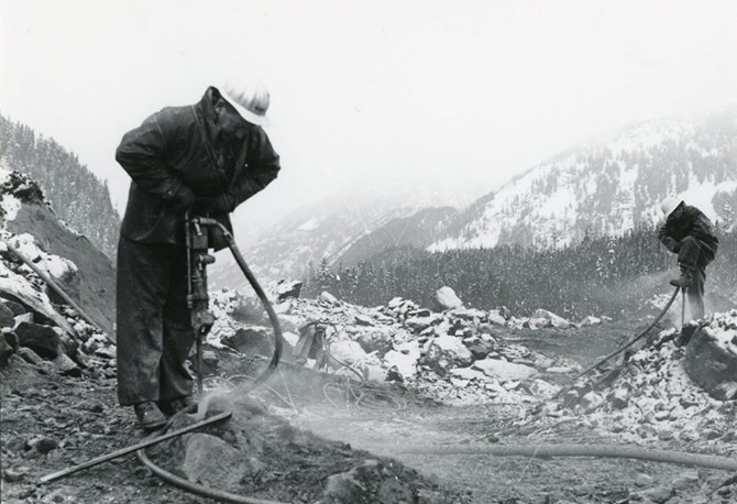 Workers drill rocks in ongoing efforts to reopen the highway after the slide.