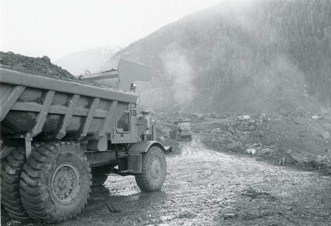 Dump trucks wheel away vast quantities of mud.